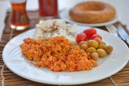 Turkish breakfast with menemen, cheese, vegetables, simit, and tea