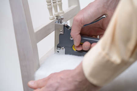 Man upholstering a chair seat using staplerの写真素材
