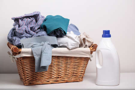 Dirty clothes in the laundry basket and a bottle of detergentの写真素材