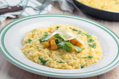 Pumpkin risotto with arugula and slices of Parmesan cheese in a bowlの写真素材