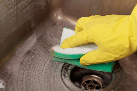 Cleaning a kitchen sink using cleaning sponge and cleanerの写真素材
