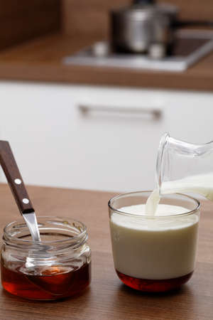 Honey and milk on a kitchen tableの写真素材
