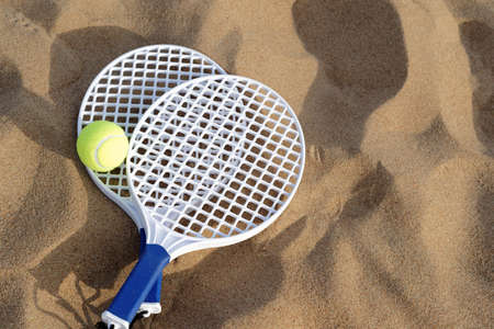 Beach tennis rackets and ball on sandの写真素材