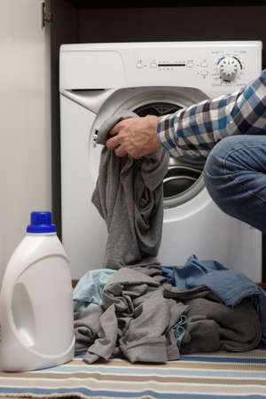 Man putting dirty clothes into opened washing machineの写真素材