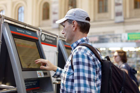 St. Petersburg, Russia - July 17, 2016: Man buying the commuter train tickets using vending machine in Baltiysky Railway station. The ticketing machines was installed here in 2009のeditorial素材