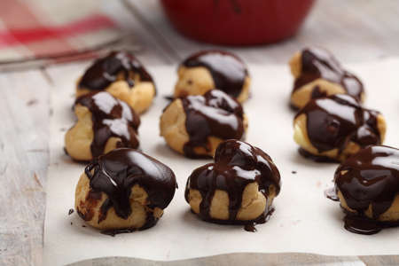 Rows of Profiteroles with chocolate glaze on a baking paperの写真素材