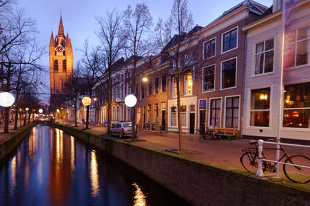 Delft, Netherlands - January 3, 2017: One of canals and Oude Kerk, Old Church in evening. Founded in XIII century, this Gothic church has a 75-meter-high brick tower that leans about two meters from the verticalのeditorial素材