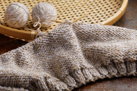 Knitting needles with unfinished hat on a rustic tableの写真素材