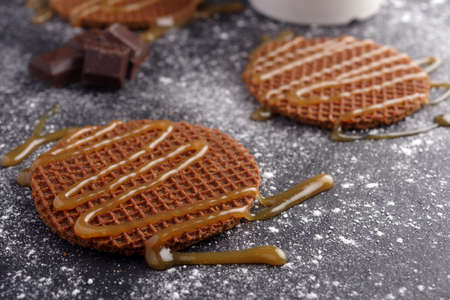 Stroopwafels with caramel sauce and chocolate on a slate surfaceの写真素材