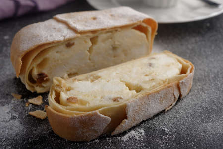 Strudel with cottage cheese and raisins under powdered sugar on a slate surfaceの写真素材
