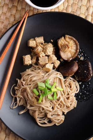 Traditional Japanese dish shiitake, soba, and tofu with soy sauce and green onion