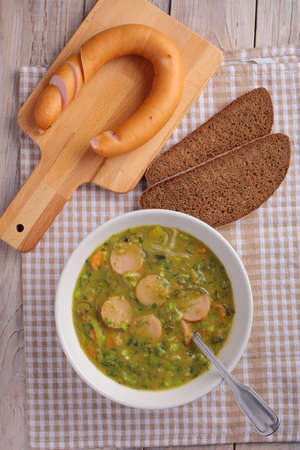 Dutch pea soup snert with smoked sausage Rookworst on a rustic tableの写真素材