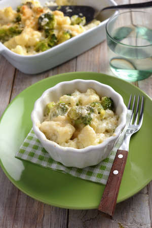 Cauliflower and broccoli cheese in a baking dish on a rustic tableの写真素材