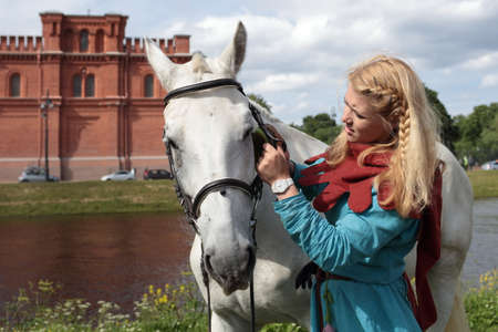St. Petersburg, Russia - July 8, 2017: Girls in medieval clothes brushing a horse before the jousting tournament during the military history project Battle On Neva at St. Peter and Paul fortress. It's the 4th such an eventのeditorial素材