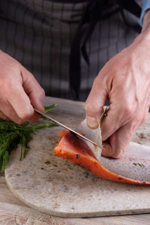Cook removing skin from salted salmon fillet on a cutting boardの写真素材