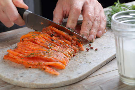 Cook slicing salted salmon on a cutting boardの写真素材