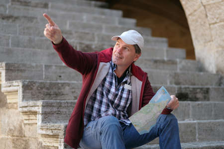 Tourist with city plan sitting on a staircase on Rhodesの写真素材