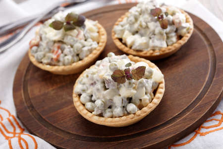 Tartlets with Russian salad on a wooden cutting board
