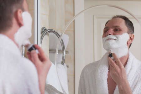 Man shaving his cheek hair using safety razorの写真素材