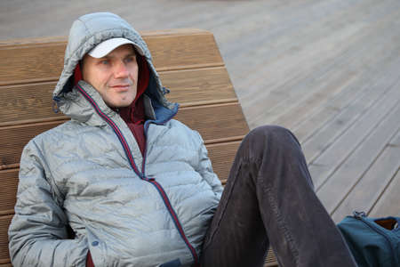 Mature man resting on a lounge chair in a city park