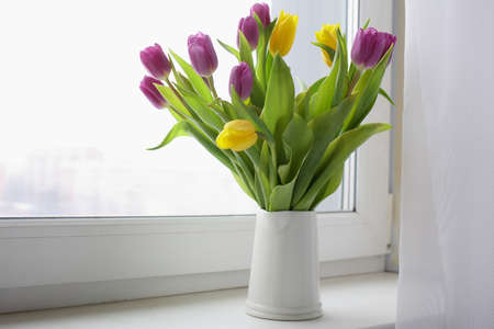 Bouquet of purple and yellow tulip flowers on a window sill
