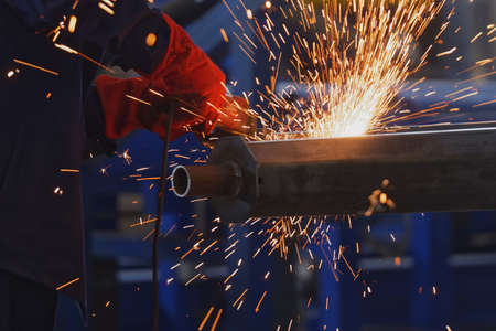 Worker grinding the steel column with hand-held grinding machine