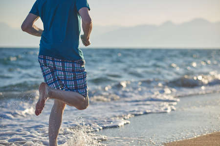 Barefoot mature man during jogging on a beachの写真素材