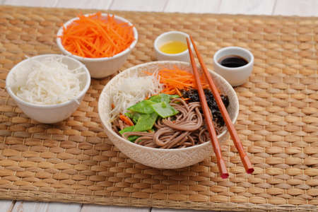 Soba noodle soup with nori seaweed sheets, green beans, carrot, daikon radish, and soy sauceの写真素材
