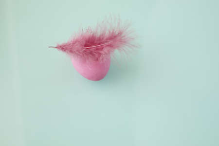 Easter egg and decorative feather looks like woman head with fluffy hat against cyan backgroundの写真素材