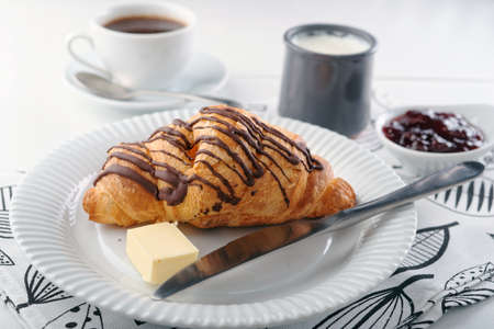 French breakfast with croissant, butter, yogurt, strawberry jam, and black coffeeの写真素材