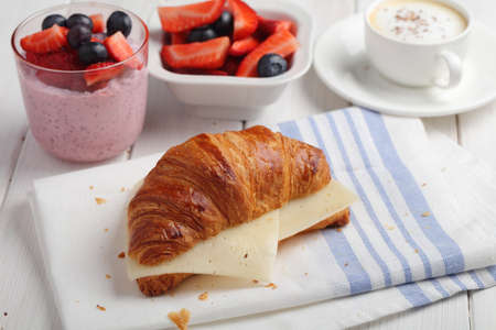 French breakfast: croissant sandwich with cheese, fruit salad, chia seeds yogurt, and a cup of cappiccinoの写真素材
