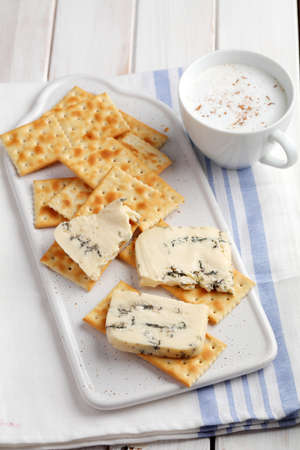 Breakfast with crackers, sliced blue cheese, and a cup of coffeeの写真素材