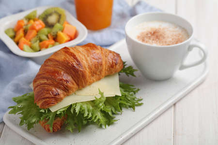 French breakfast: croissant sandwich with cheese, fruit salad, and a cup of cappuccinoの写真素材