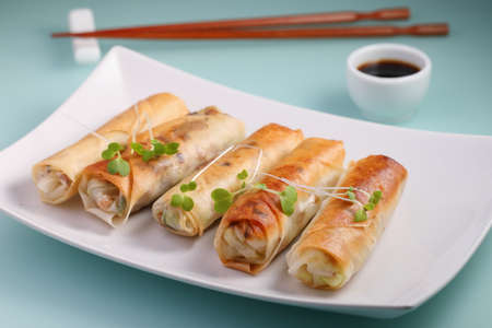 Spring rolls topped with sprouts and served with soy sauce