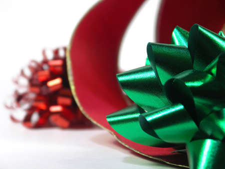 red and green bow with curling red ribbon isolated on white. shallow depth of field. focus on green bow.の写真素材