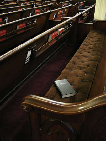 Bible on empty pew. Focused on bible. Empty church with lots of pews.の写真素材