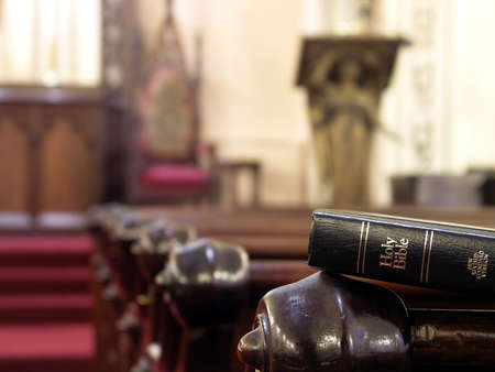 Bible resting on the back of a church pew. Shallow DOF with sharp focus on bible.の写真素材