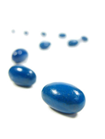 blue jelly beans in a trail on white.の写真素材