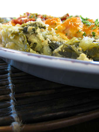 chicken and greens in a red sauce on a platter on a bamboo placemat.の写真素材