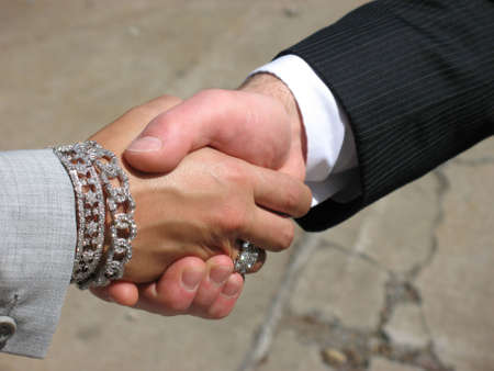 Business woman and man shaking hands against and urban background