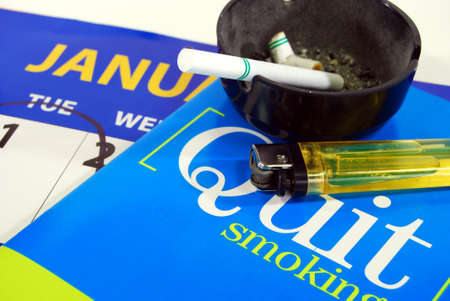 Cigarette in ashtray with lighter and stop smoking literature on calendar with January 1st circled. の写真素材