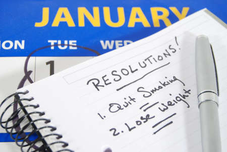 A calendar opened to January with the first circled, a notebook with two New Year's resolutions...