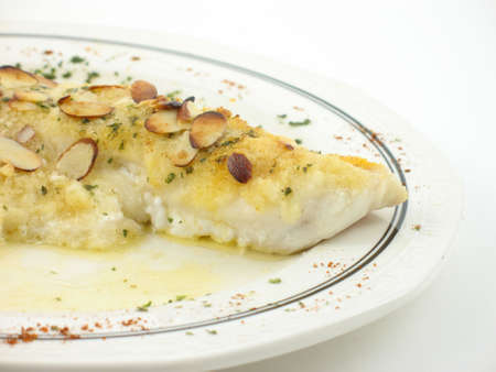 Fish with almonds on a white plate on a white background