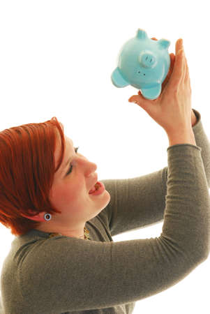 Attractive Caucasian woman looking up into piggy bank.
