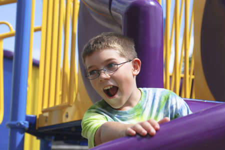 Attractive Caucasian boy on a slide in a playground with a surprised expression.の写真素材