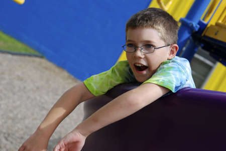 Young Caucasian boy on playground equipment with mouth open.の写真素材