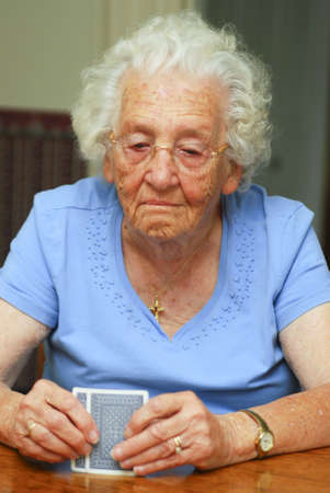 Senior woman holding cards looking at them with thoughtful expressionのeditorial素材