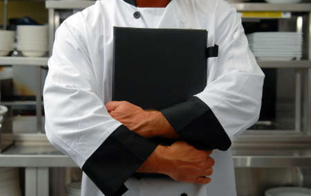 A chef holds a menu in a restaurant kitchenの写真素材