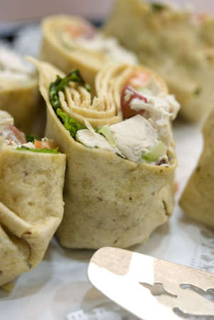 Chicken salad wraps and a spatula at a buffet-style lunch. Shallow DOF. Focus on top of center wrap.の写真素材