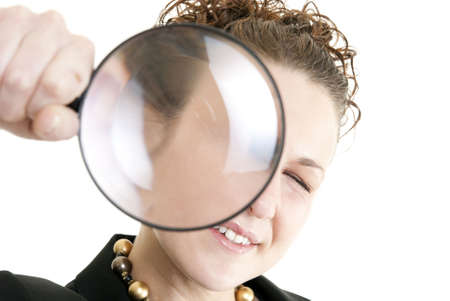 Business woman holding a magnifying glass isolated on white. Focus on face.の写真素材